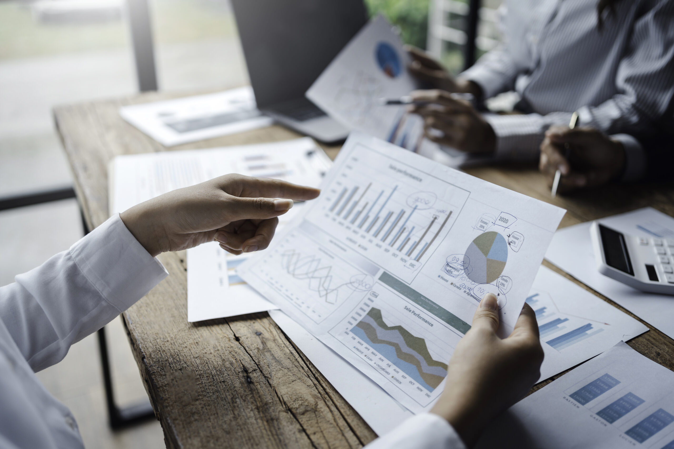 Close-up of business team reviewing performance charts during an M&A planning meeting.